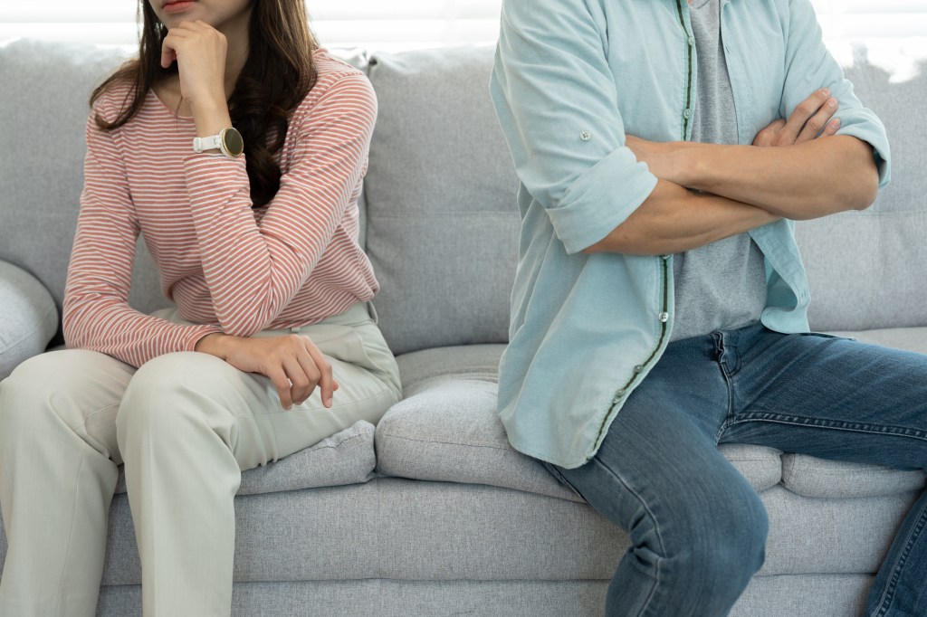 A depressed man and woman sitting on a couch, dealing with marital problems and disappointment